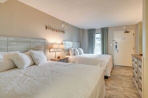 A hotel room with two beds, a nightstand with a lamp, a dresser, and a door with a lock. - Oceanfront Balcony: Resort Condo in Myrtle Beach (Myrtle Beach)