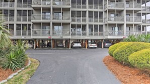 Un hôtel à plusieurs étages doté de balcons, d’un parking et d’un jardin bien entretenu.