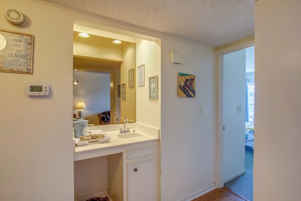 Une salle de bain avec un lavabo blanc, un miroir et un tableau encadré au mur.