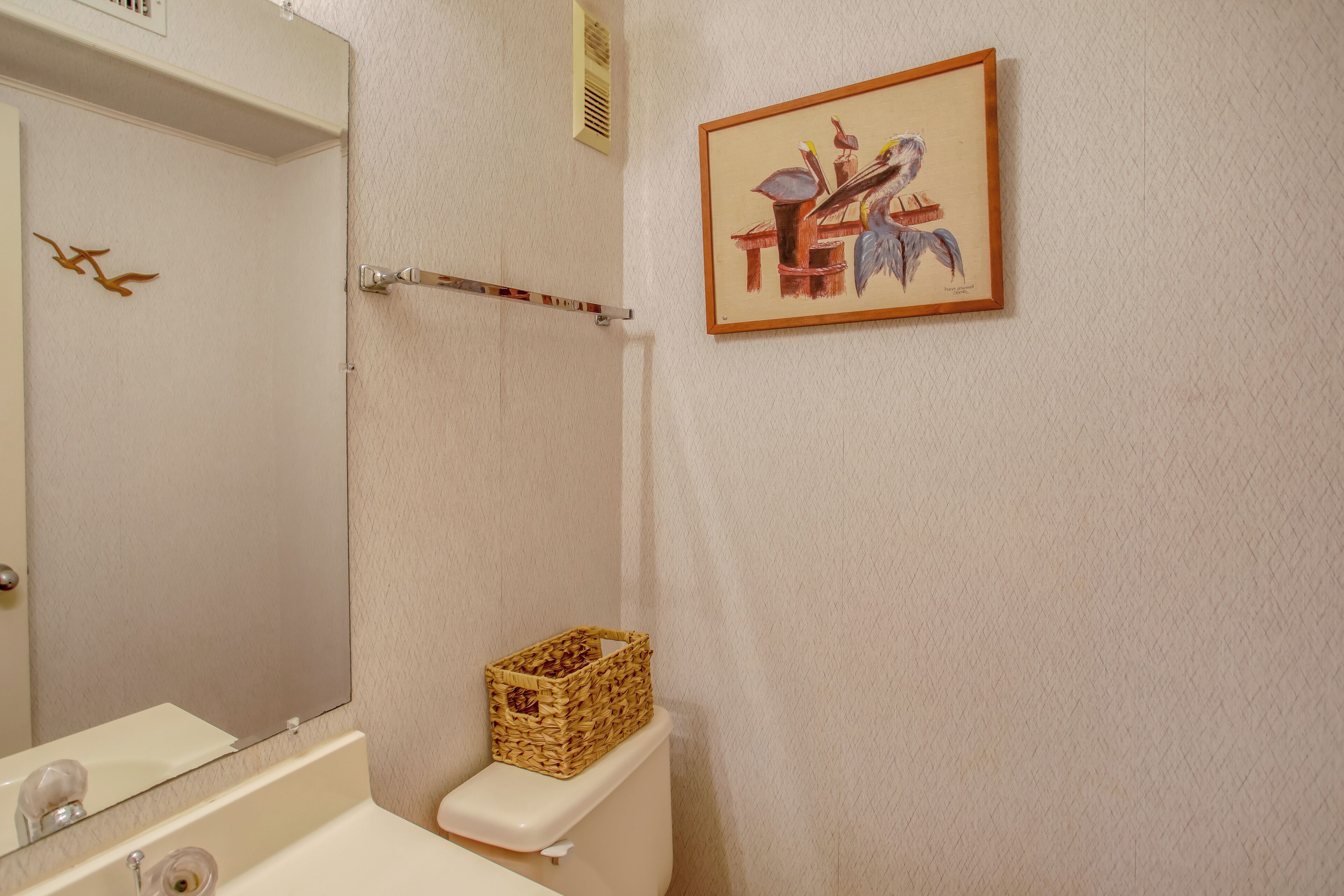 A bathroom with a white bathtub, a toilet, and a wall-mounted basket.