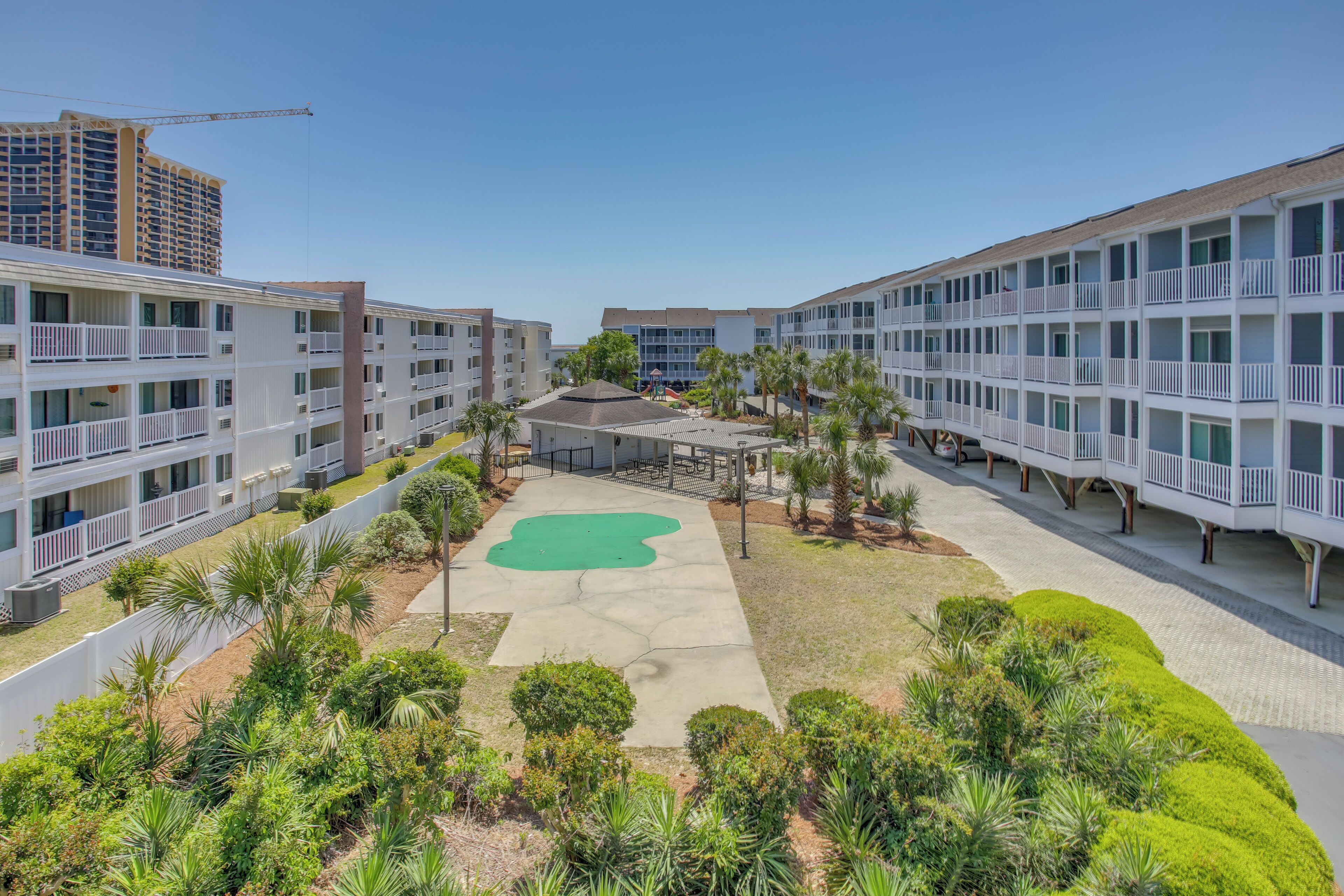 Un hotel con diversi piani, zone salotto all'aperto e un cortile centrale con un'area verde.