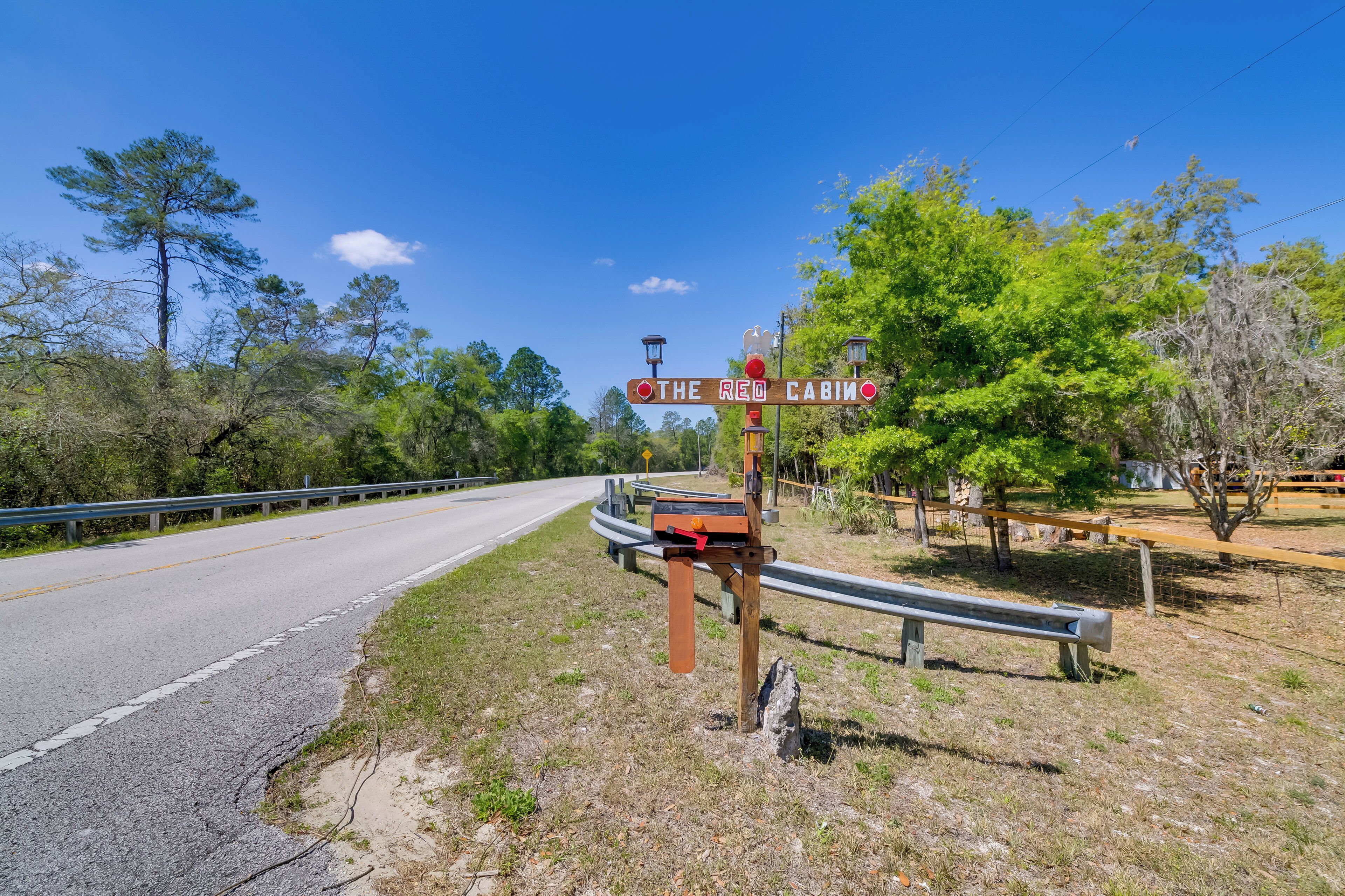A road sign for "The Red Cabin" with a wooden structure and a bench nearby.