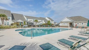 A swimming pool with lounge chairs and a building in the background.