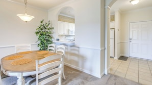 A dining area with a table, chairs, and a hanging light fixture.