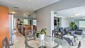 A modern kitchen with a central island, a dining area with a glass table, and a living room with a grey sofa and a plant. - Punta Gorda Escape w/ Private Lanai & Pool! (Punta Gorda)