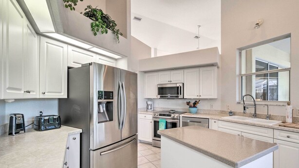 A modern kitchen with stainless steel appliances, white cabinetry, and a large island. - Port Charlotte Home on Canal w/ Lanai & Pool! (Port Charlotte)
