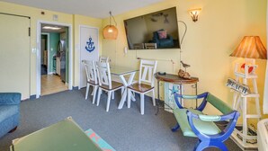 A room with a dining table and chairs, a television, a lamp, and a beach-themed decoration. - Myrtle Beach Oceanfront Condo w/ Pool & Lazy River (Myrtle Beach)