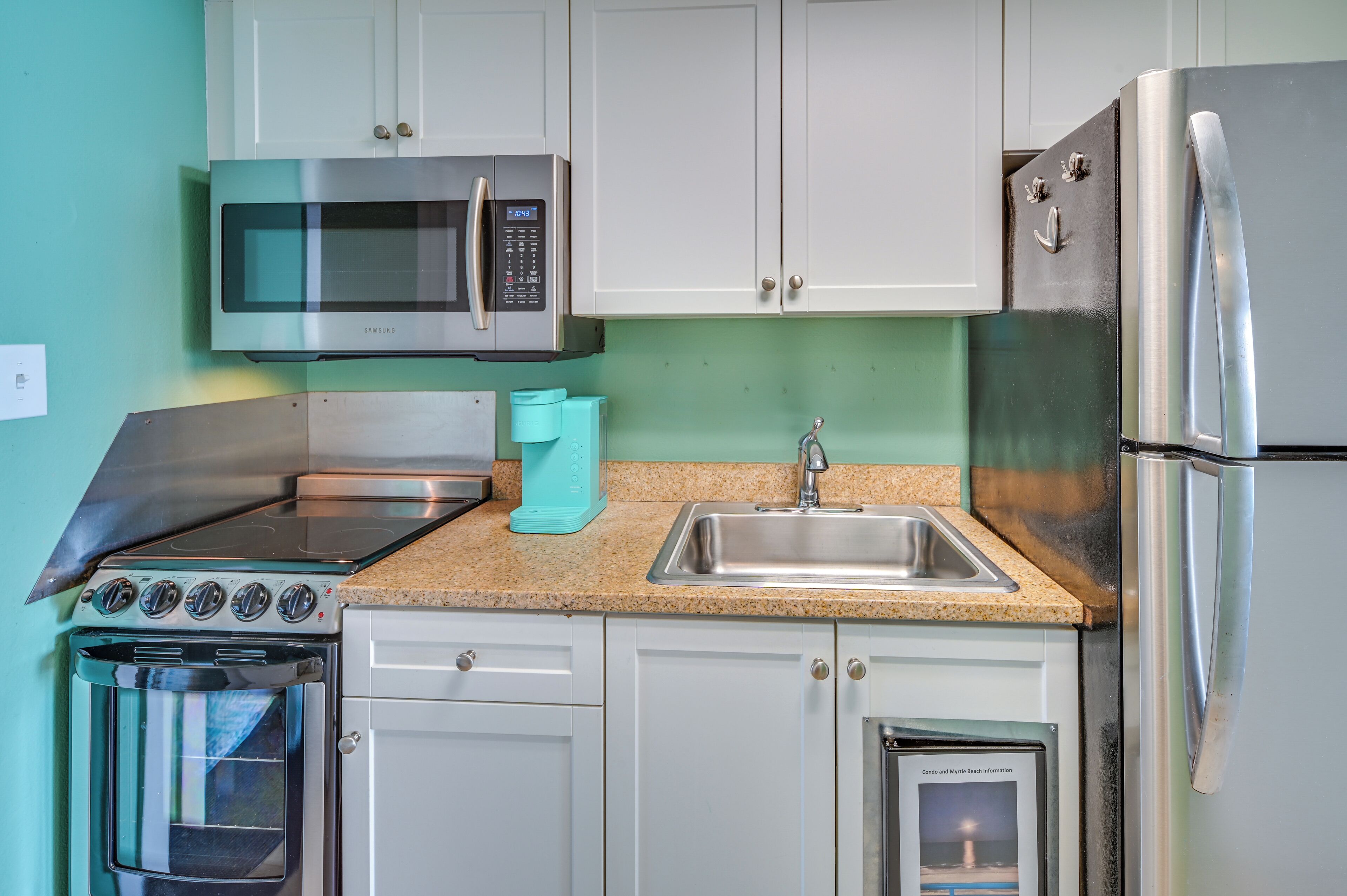 A kitchen with a microwave, stove, sink, and refrigerator.