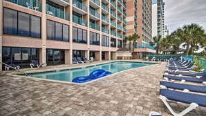 A hotel pool area with lounge chairs and a blue inflatable float. - Myrtle Beach Oceanfront Condo w/ Pool & Lazy River (Myrtle Beach)