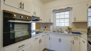 Een moderne keuken met witte kastjes, een roestvrijstalen oven, een spoelbak en een raam met uitzicht.