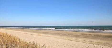 A beach with a clear sky, sandy shore, and a sign indicating a discharge area.