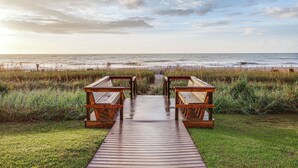 Une promenade en bois qui mène à des espaces de détente situés au bord de la plage.