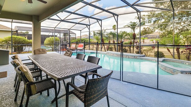 Ein überdachter Außenbereich mit Pool, Tisch und Stühlen sowie einem Deckenventilator.