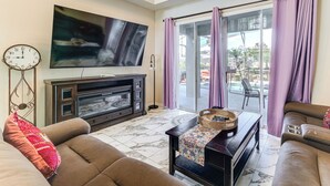 Ein Wohnzimmer mit Flachbildfernseher, Kamin, einer Couch und einem Essbereich mit Tisch und Stühlen.