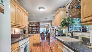 A spacious kitchen with wooden cabinets, granite countertops, and a central island. - Rustic Beaufort Home w/ Stunning Marsh Views! (Beaufort)
