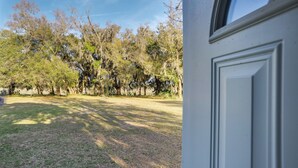 A view of a lawn with trees and a white door. - Saint Helena Island Getaway w/ Marsh Views! (Saint Helena Island)