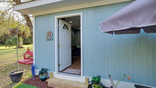 A small, single-story building with a blue exterior, a wooden door, and a welcome sign. - Saint Helena Island Getaway w/ Marsh Views! (Saint Helena Island)