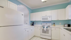 A kitchen with white cabinets, a white refrigerator, a microwave, an oven, and a toaster.