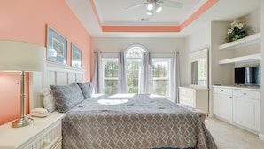 A bedroom with a bed, nightstand, lamp, and a television on a stand.