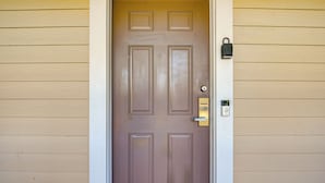 A closed wooden door with a keyhole and a doorbell.
