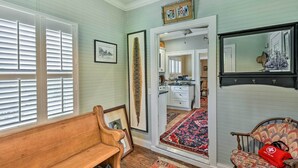 A room with a wooden bench, a red bag, a patterned rug, and a mirror on the wall. - Ridgeland Vacation Rental < 30 Mi to Beaufort (Ridgeland)