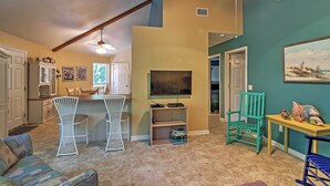 A living room with a TV, two white chairs, a teal wall, and a ceiling fan. - Santa Rosa Beach Bungalow 5 Mi to the Gulf Shore! (Santa Rosa Beach)