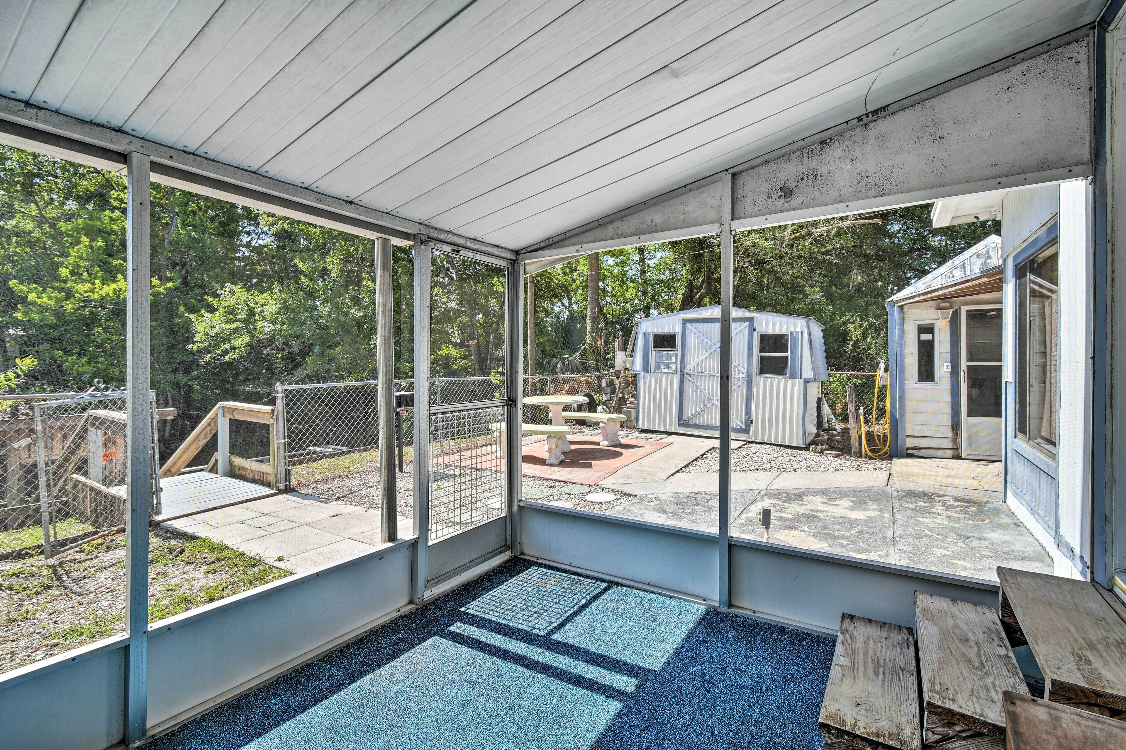 Un espacio al aire libre techado con vista a una casa móvil y un área de juegos cercada.