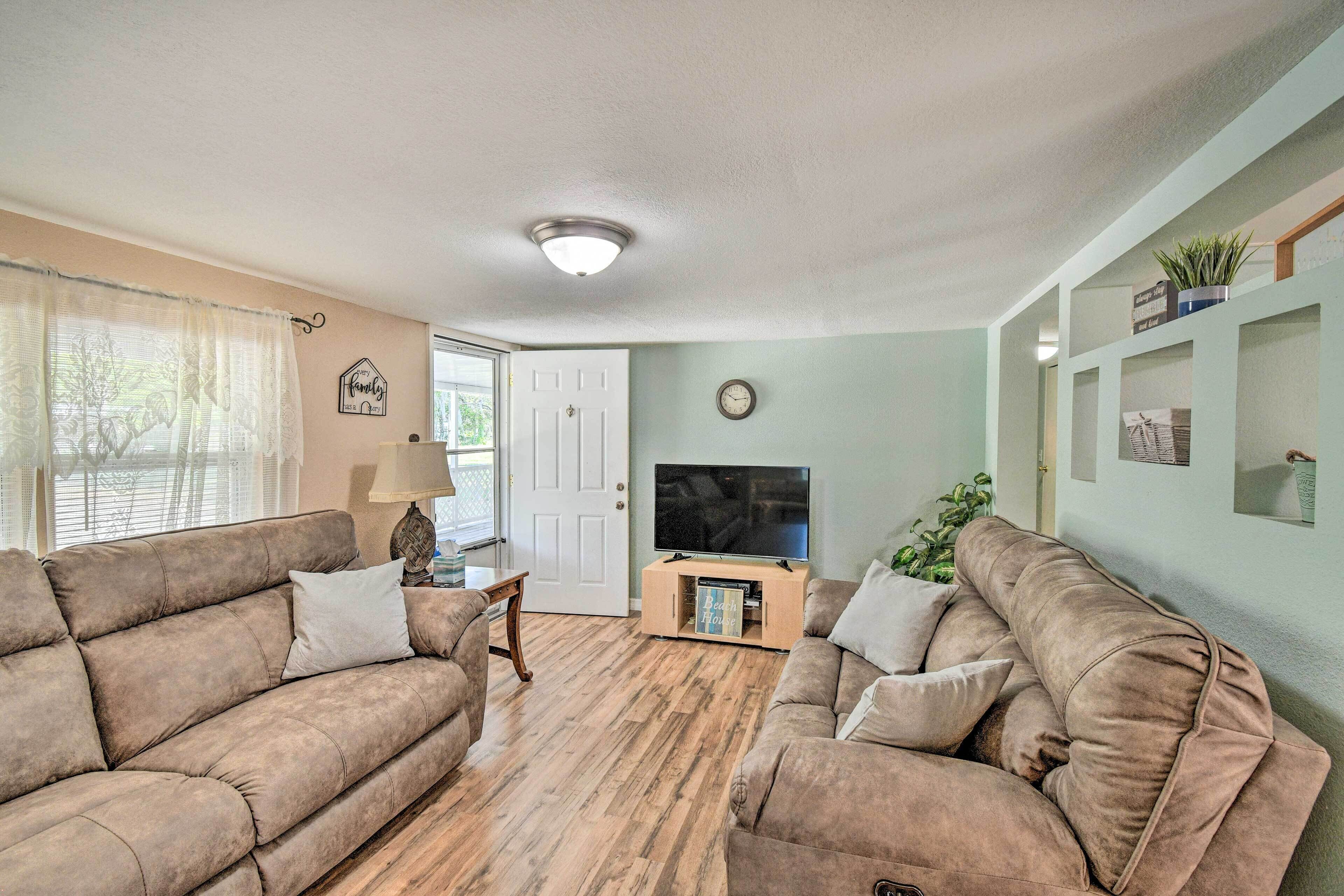 A living room with two brown sofas, a wooden coffee table, a TV on a stand, and a door leading outside.