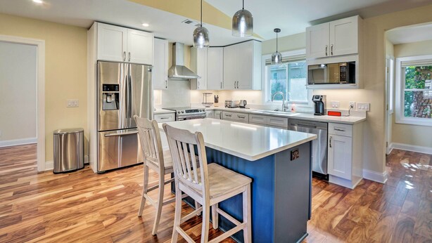 A modern kitchen with a central island, stainless steel appliances, and pendant lighting.