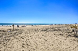 A wide sandy beach with footprints and a few people.
