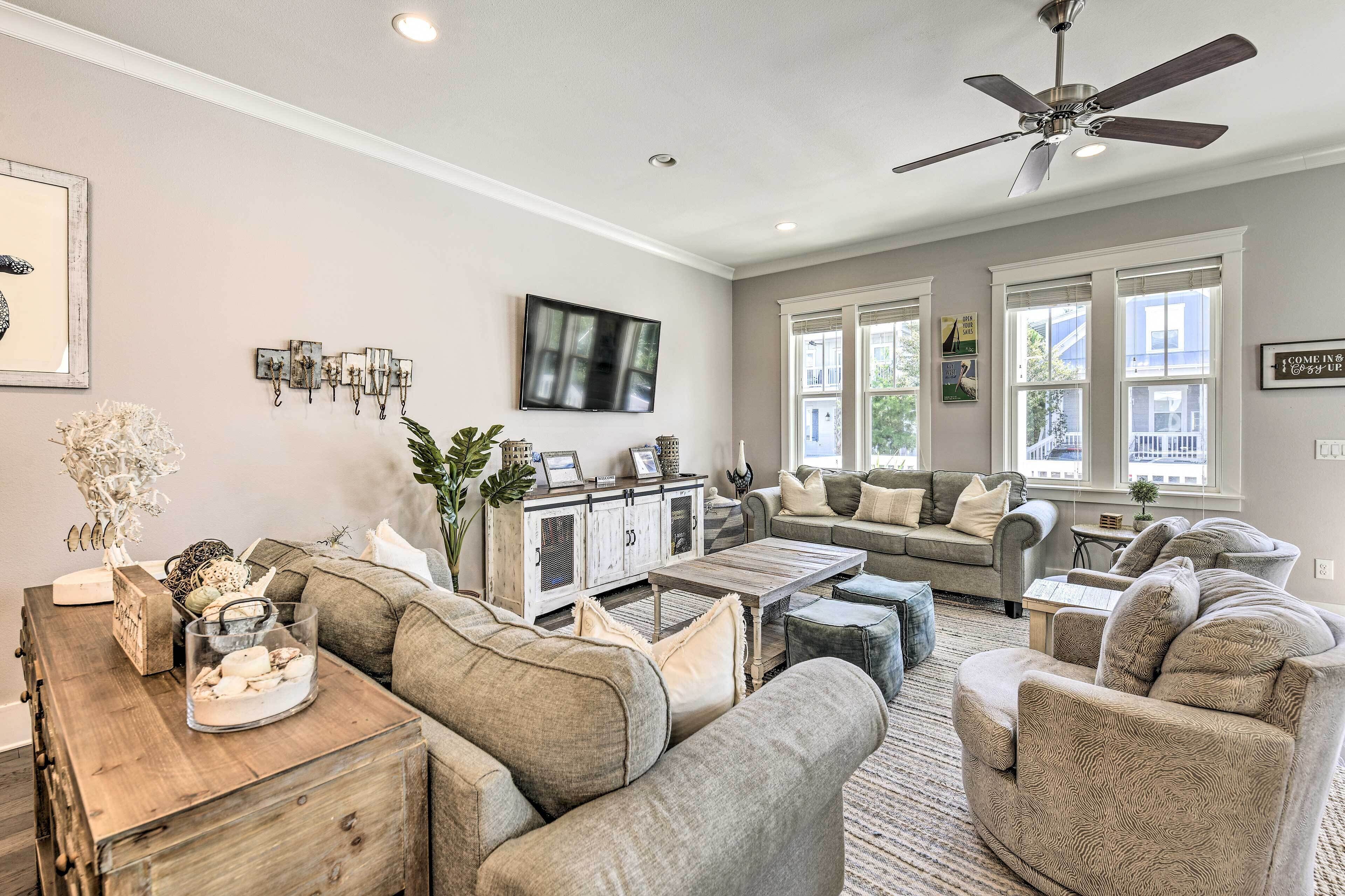A spacious living room with a large sofa set, a wooden coffee table, and a television mounted on the wall.