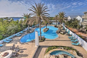 Ein Poolbereich mit Liegestühlen, Palmen und Blick auf das Meer.