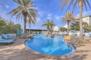 A swimming pool with lounge chairs and palm trees, surrounded by a building with a white facade. - Santa Rosa Beach Retreat w/ Endless Amenities (Santa Rosa Beach)