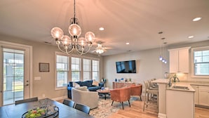 A spacious living room with a dining area, a kitchen with a large island, and a ceiling fan. - Luxury Barefoot Resort Retreat: Pool, Marina Views (North Myrtle Beach)