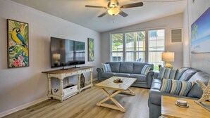 A living room with a TV, a sofa, a coffee table, and artwork on the walls. - 'sarasota Sunset House' w/ Spacious Patio! (Sarasota)