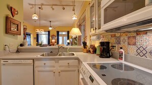 A kitchen with a dishwasher, stove, and sink. There are hanging lights and a window with curtains. - Riverside Cottage: Close to Ocean and Myrtle Beach (Murrells Inlet)