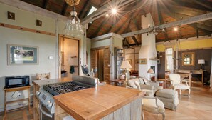 A spacious kitchen with a central island, wooden ceiling beams, and a dining area with chairs and a table. - Views & Trails: Horse Farm Home in Campobello! (Campobello)