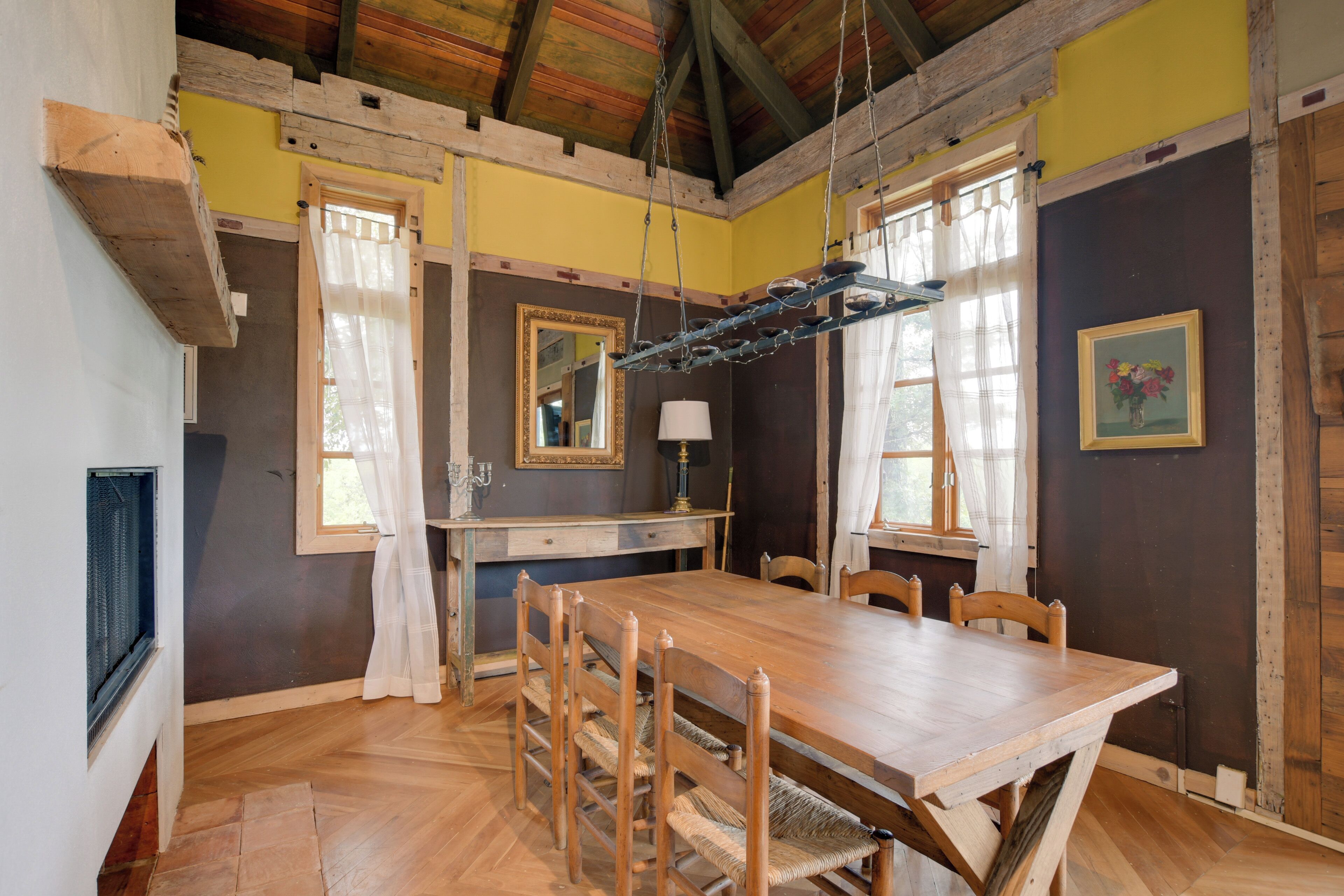 Un comedor con una mesa y sillas de madera, una lámpara colgante y una ventana con cortinas.
