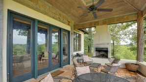 An outdoor patio with a fireplace, seating, and a view of the landscape. - Views & Trails: Horse Farm Home in Campobello! (Campobello)