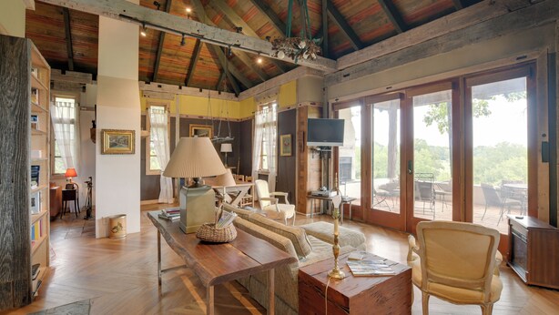 A spacious living room with a wooden ceiling, a large window, and a television. - Views & Trails: Horse Farm Home in Campobello! (Campobello)