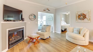 A living room with a fireplace, a TV, a ceiling fan, and a view into the bedroom. - < 2 Mi to Beach: Savannah Shores Resort Condo! (Myrtle Beach)