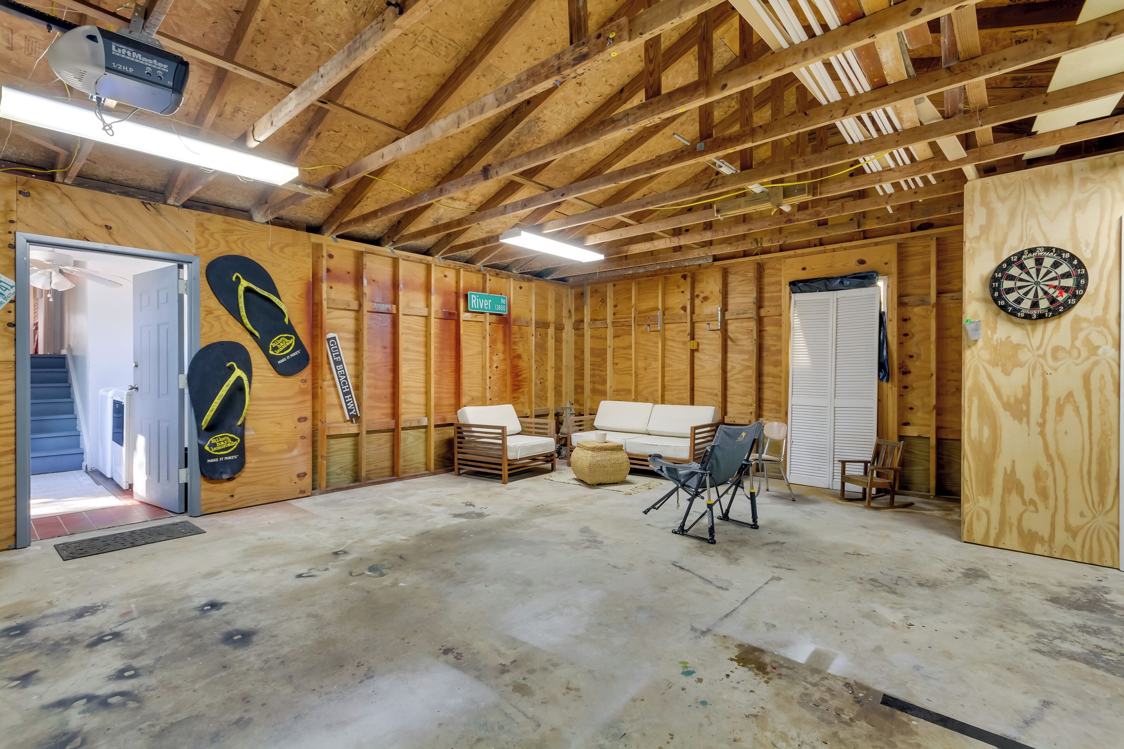 Une pièce aux murs en bois, avec un canapé, un fauteuil et un jeu de fléchettes.