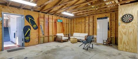 Une pièce aux murs en bois, avec un canapé, un fauteuil et un jeu de fléchettes.