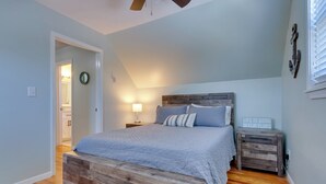 Ein Schlafzimmer mit einem hölzernen Bett, einem Nachttisch, einer Wanduhr und einem Deckenventilator.
