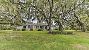 A large house with a porch, surrounded by a well-maintained lawn and mature trees with Spanish moss. - Waterfront Home w/ Shared Dock on Okatie River (Bluffton)