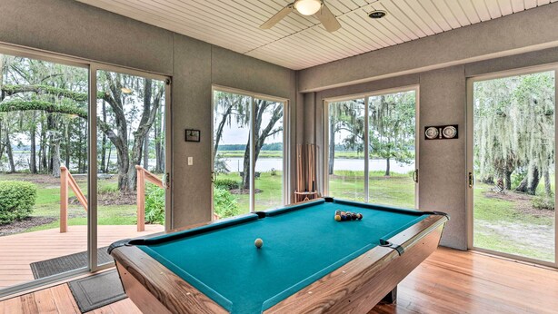 A pool table with a view of a lake and trees through large windows. - Waterfront Home w/ Shared Dock on Okatie River (Bluffton)