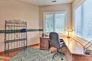 Un dormitorio con cama, escritorio, silla y ventana con persianas.