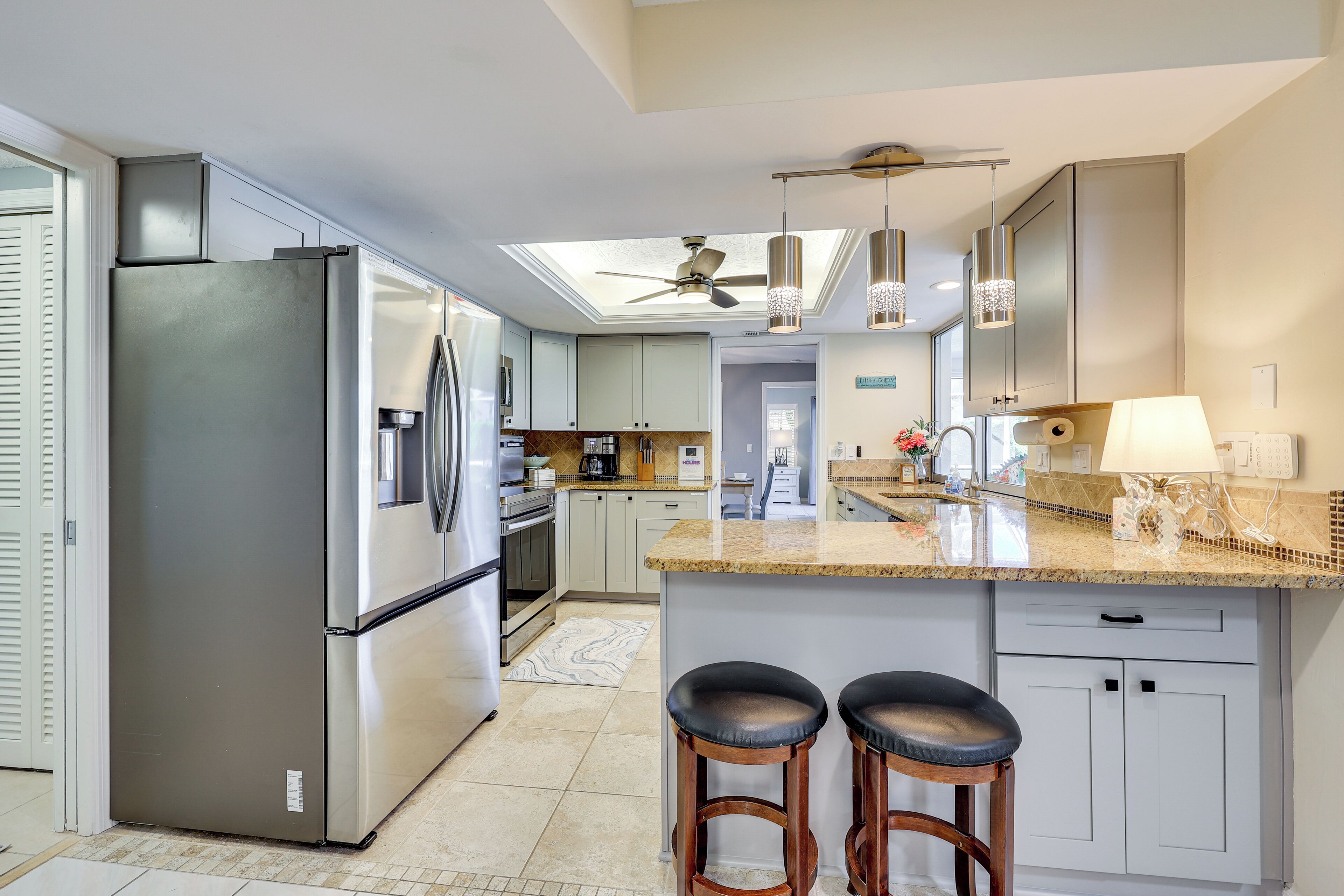 A modern kitchen with a large island, stainless steel appliances, and a skylight.