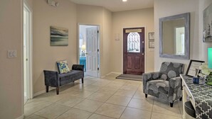A spacious hallway with a bench, a patterned armchair, and a door leading to another room. - Spacious Clermont Getaway ~ 10 Miles to Disney! (Clermont)