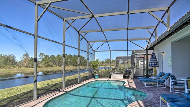 A covered outdoor swimming pool with lounge chairs and a view of a lake. - Spacious Clermont Getaway ~ 10 Miles to Disney! (Clermont)